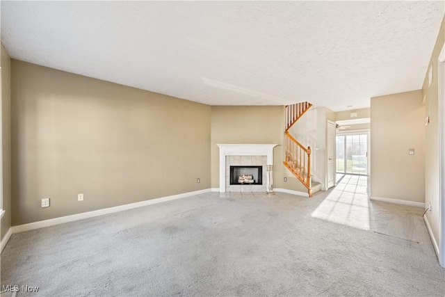 unfurnished living room with light carpet, a textured ceiling, and a tiled fireplace