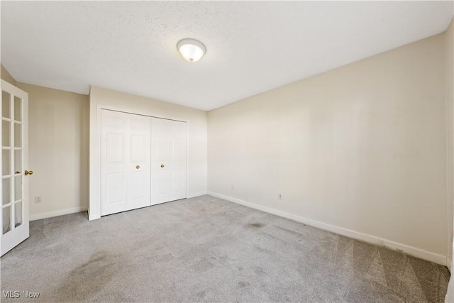 unfurnished bedroom featuring carpet, a textured ceiling, and a closet