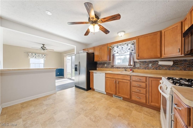 kitchen featuring decorative backsplash, a textured ceiling, white appliances, ceiling fan, and sink