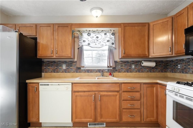 kitchen with a textured ceiling, white appliances, tasteful backsplash, and sink