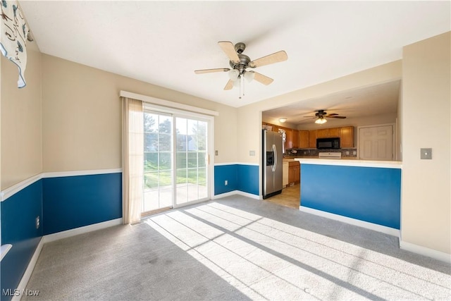 kitchen with stainless steel fridge, light colored carpet, and kitchen peninsula