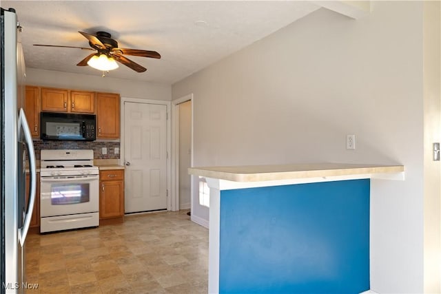 kitchen featuring decorative backsplash, ceiling fan, white stove, and stainless steel refrigerator