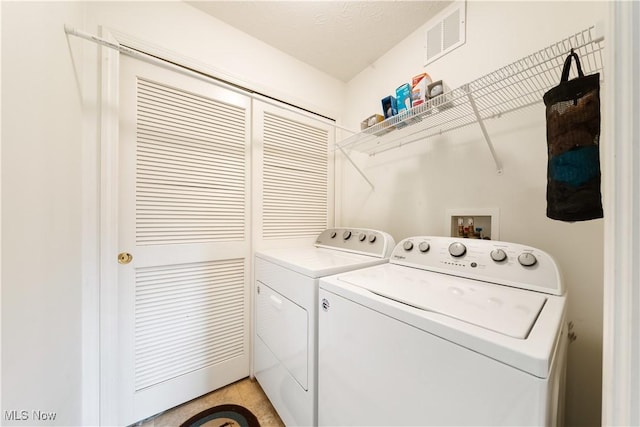 laundry area with a textured ceiling and washing machine and dryer