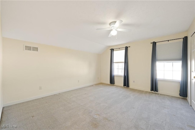 unfurnished room featuring light carpet, a healthy amount of sunlight, and vaulted ceiling