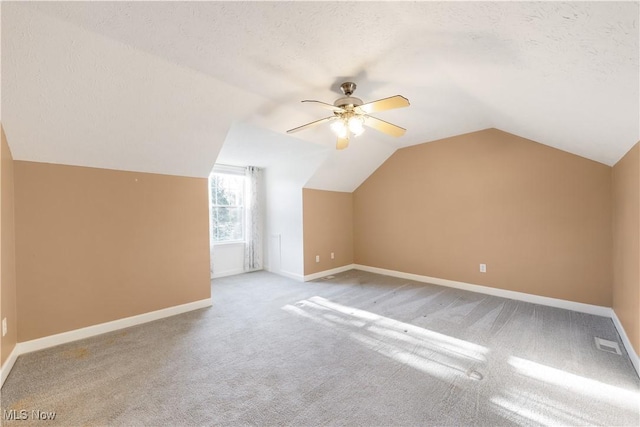 bonus room featuring a textured ceiling, light colored carpet, and lofted ceiling