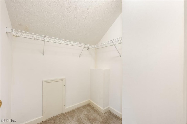 walk in closet featuring light colored carpet and vaulted ceiling