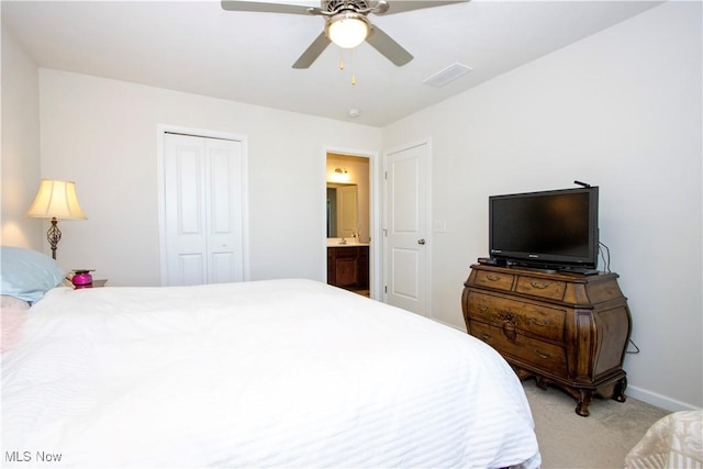 carpeted bedroom featuring a closet, ensuite bath, and ceiling fan