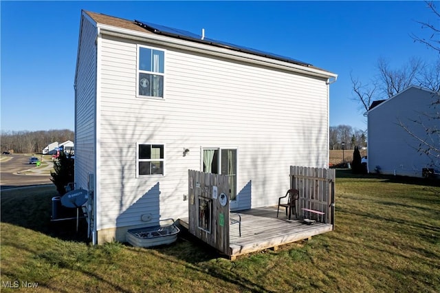 back of property featuring solar panels, a yard, and a wooden deck