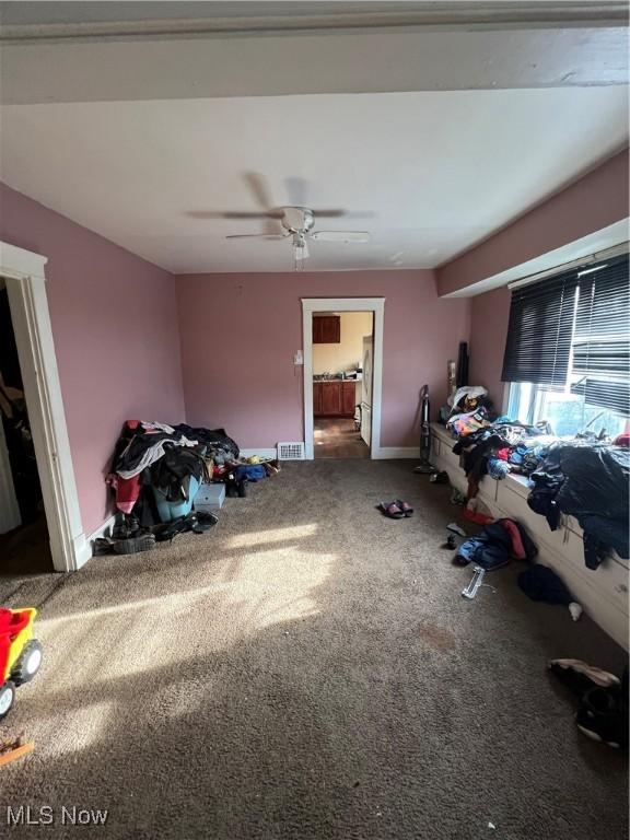 interior space with carpet flooring and ceiling fan