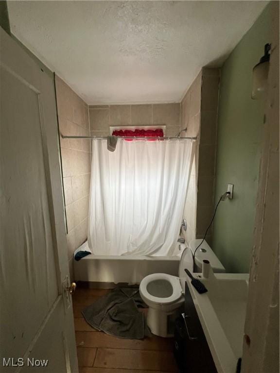 bathroom featuring shower / bath combo, toilet, and a textured ceiling