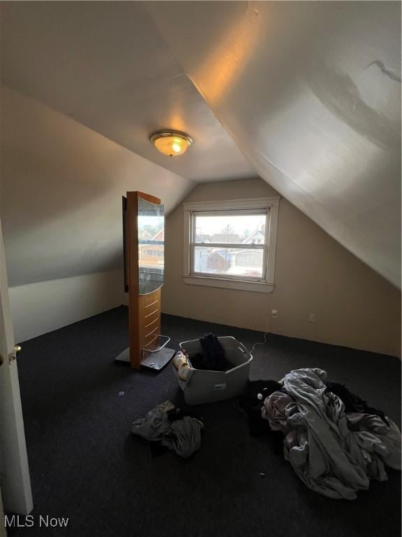 bonus room featuring vaulted ceiling and dark colored carpet