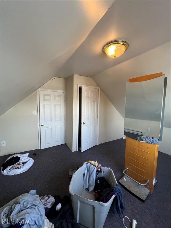 additional living space featuring dark colored carpet and vaulted ceiling