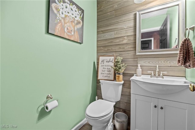 bathroom featuring wooden walls, vanity, and toilet