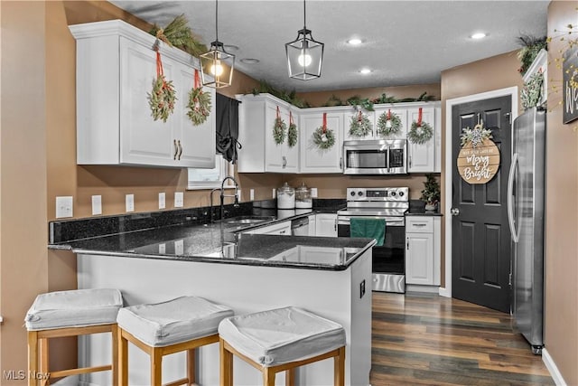 kitchen featuring kitchen peninsula, appliances with stainless steel finishes, a breakfast bar, and decorative light fixtures