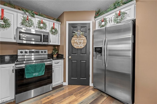 kitchen featuring light wood-type flooring, a textured ceiling, stainless steel appliances, and white cabinets