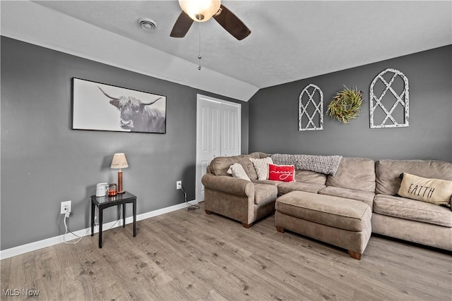 living room with a textured ceiling, light hardwood / wood-style floors, vaulted ceiling, and ceiling fan