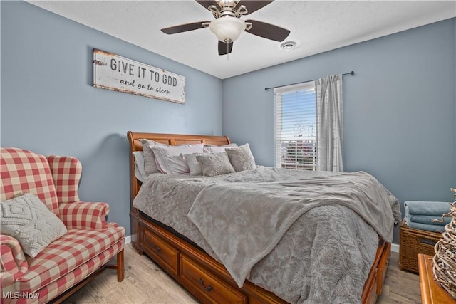 bedroom with ceiling fan, light wood-type flooring, and a textured ceiling