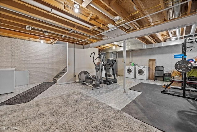 workout area with separate washer and dryer and brick wall