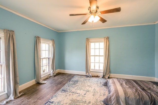 unfurnished bedroom featuring ceiling fan, wood-type flooring, crown molding, and multiple windows