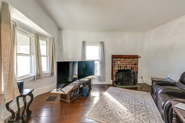 living room featuring dark wood-type flooring, a healthy amount of sunlight, and a brick fireplace