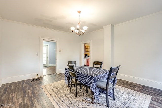 dining area with crown molding, dark wood-type flooring, and a notable chandelier