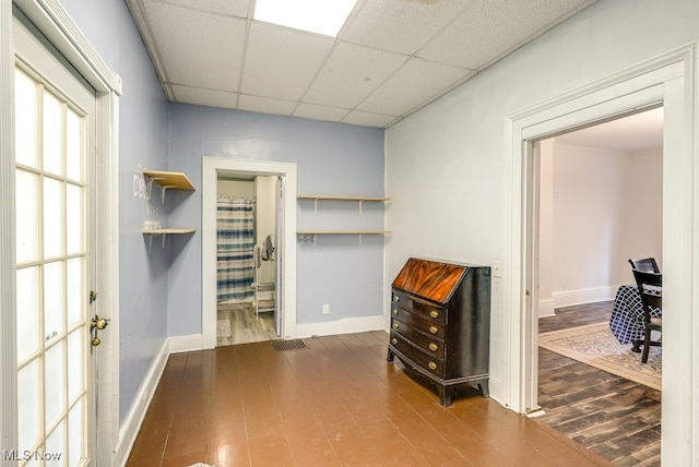 interior space featuring a paneled ceiling and hardwood / wood-style flooring