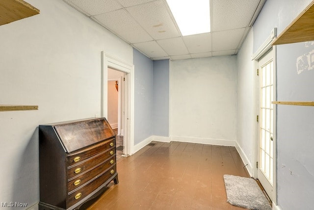 interior space featuring a drop ceiling and wood-type flooring