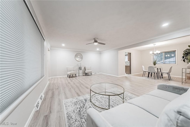 living room with ceiling fan with notable chandelier and light hardwood / wood-style flooring