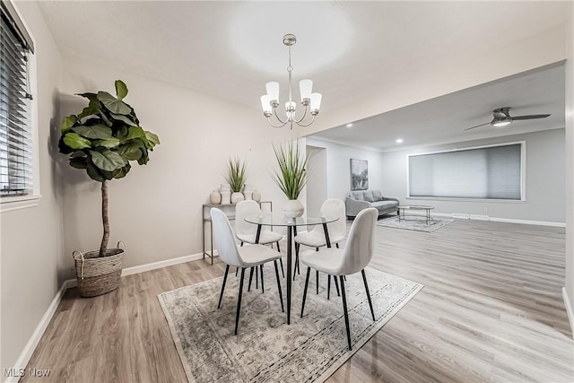 dining room with hardwood / wood-style floors and ceiling fan with notable chandelier