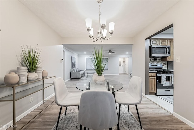 dining room with ceiling fan with notable chandelier and light wood-type flooring