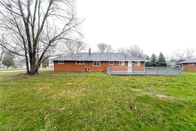 rear view of house with a lawn and a wooden deck