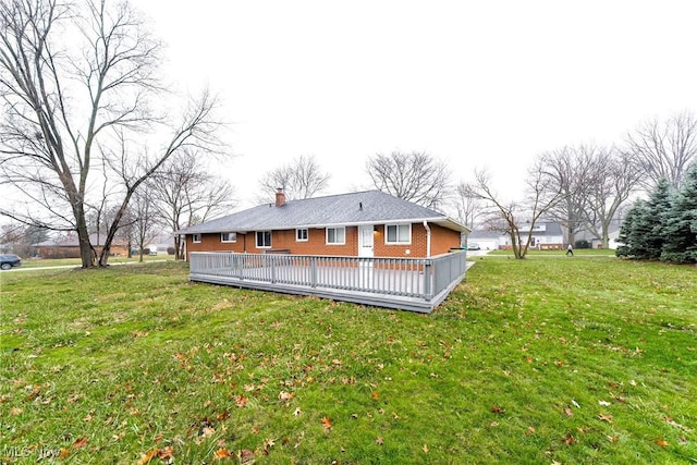 rear view of house featuring a lawn and a wooden deck