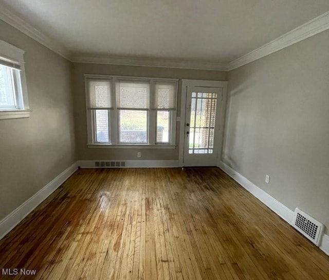 unfurnished room with hardwood / wood-style floors, a healthy amount of sunlight, and ornamental molding