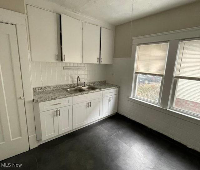 kitchen featuring white cabinets, light stone countertops, and sink