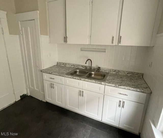 kitchen featuring white cabinets, tasteful backsplash, light stone counters, and sink