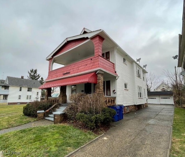 view of front of house featuring a porch, a garage, an outbuilding, and a front lawn