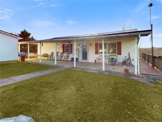 rear view of house featuring a lawn and covered porch