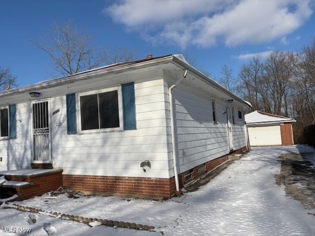 view of snowy exterior featuring a garage and an outdoor structure