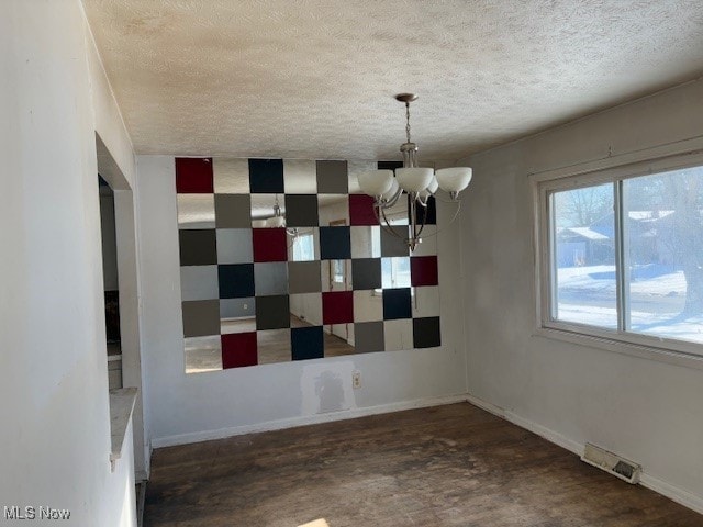 unfurnished dining area with a chandelier and a textured ceiling