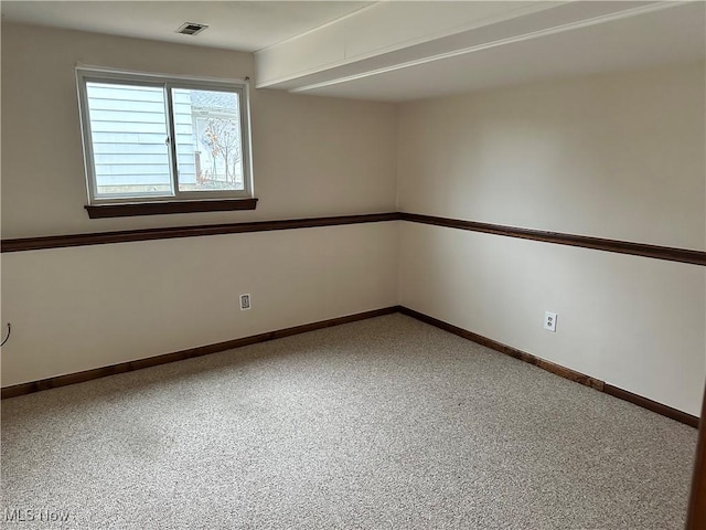 empty room featuring beamed ceiling and carpet