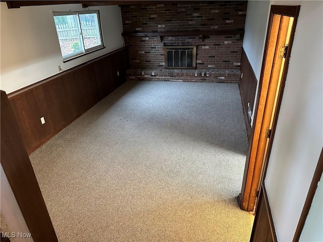 unfurnished living room with wood walls, light colored carpet, and a fireplace