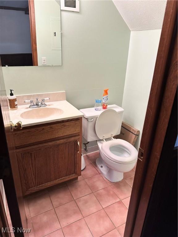 bathroom featuring tile patterned flooring, vanity, a textured ceiling, and toilet