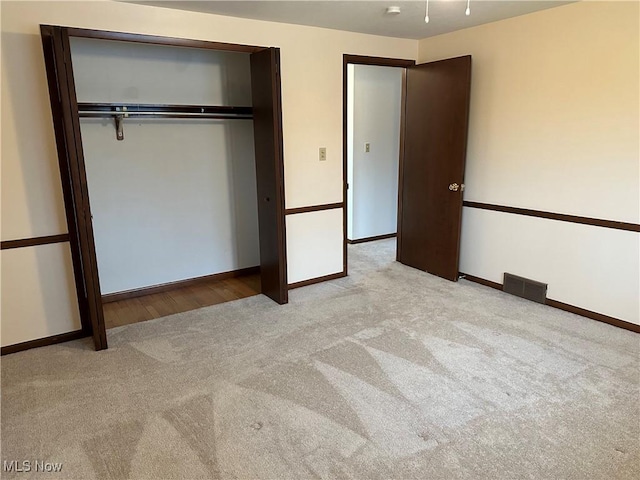 unfurnished bedroom with light carpet and a closet