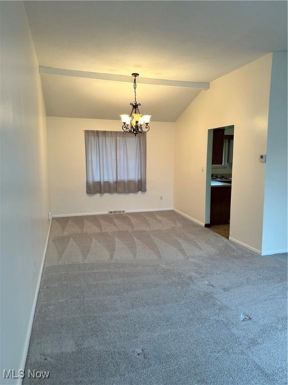 carpeted spare room with vaulted ceiling and an inviting chandelier