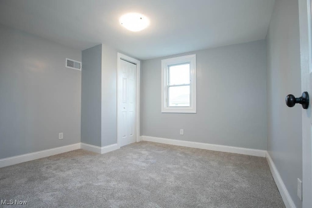 unfurnished bedroom featuring light colored carpet and a closet