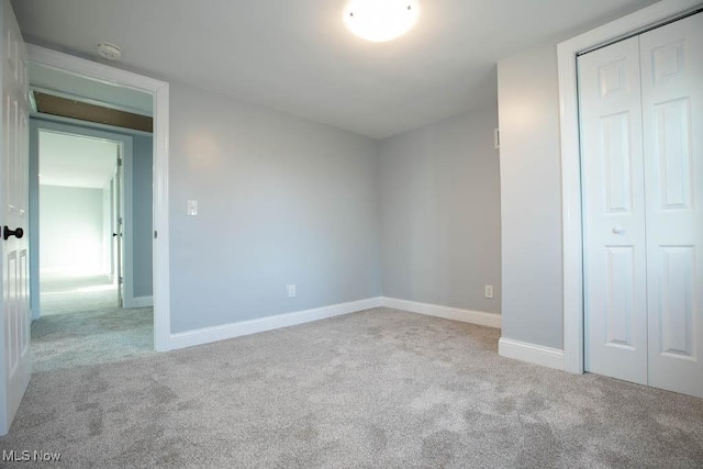 unfurnished bedroom with a closet and light colored carpet