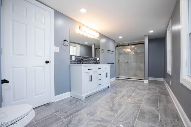 bathroom featuring vanity, toilet, walk in shower, and backsplash