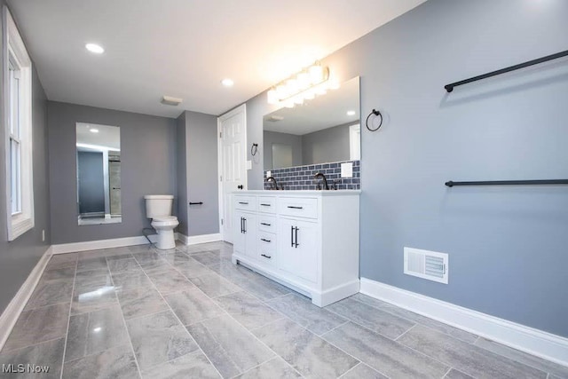 bathroom featuring backsplash, vanity, and toilet