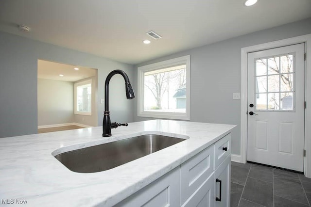 kitchen featuring white cabinetry, sink, and light stone counters