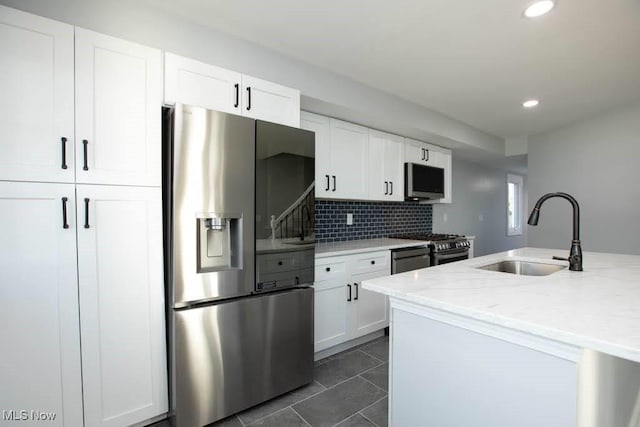 kitchen featuring sink, light stone countertops, tasteful backsplash, white cabinetry, and stainless steel appliances